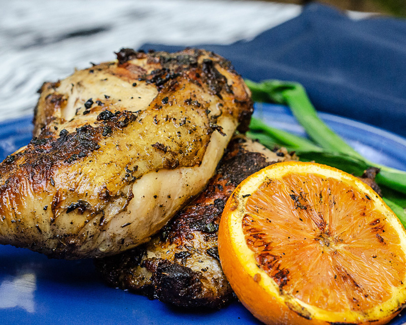 BBQ Chicken with jerk marinade. A grilled orange sits next to it