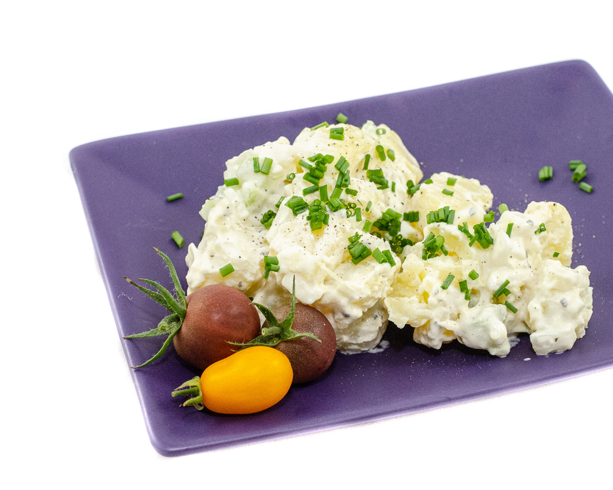 A plate with potato salad and tomatoes