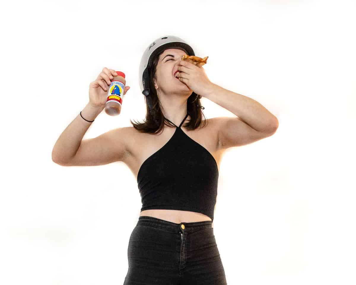 woman eating hot wing and holding habanero hot sauce