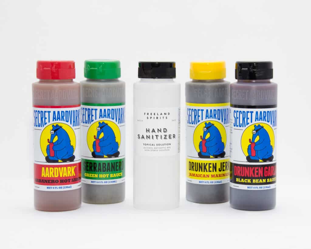 Bottles of Secret Aardvark sauces (Drunken Jerk, Aardvark Habanero, Drunken Garlic, and Serrabanero) and hand sanitizer