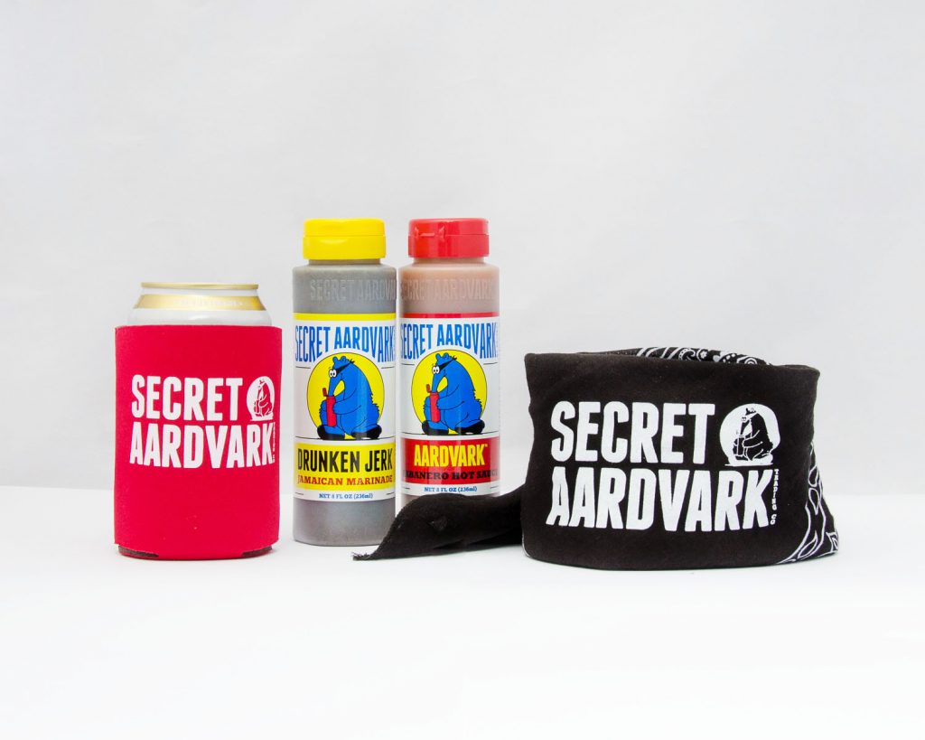 Red secret aardvark koozie, bottle of aardvark hot sauce, bottle of drunken jerk marinade, black secret aardvark bandana