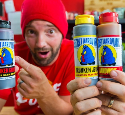 Person holding Secret Aardvark sauces and pointing excitedly to Drunken Garlic sauce