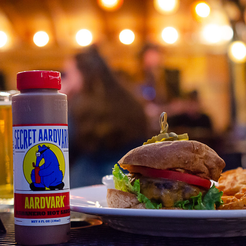 Bottle of aardvark sauce next to a burger
