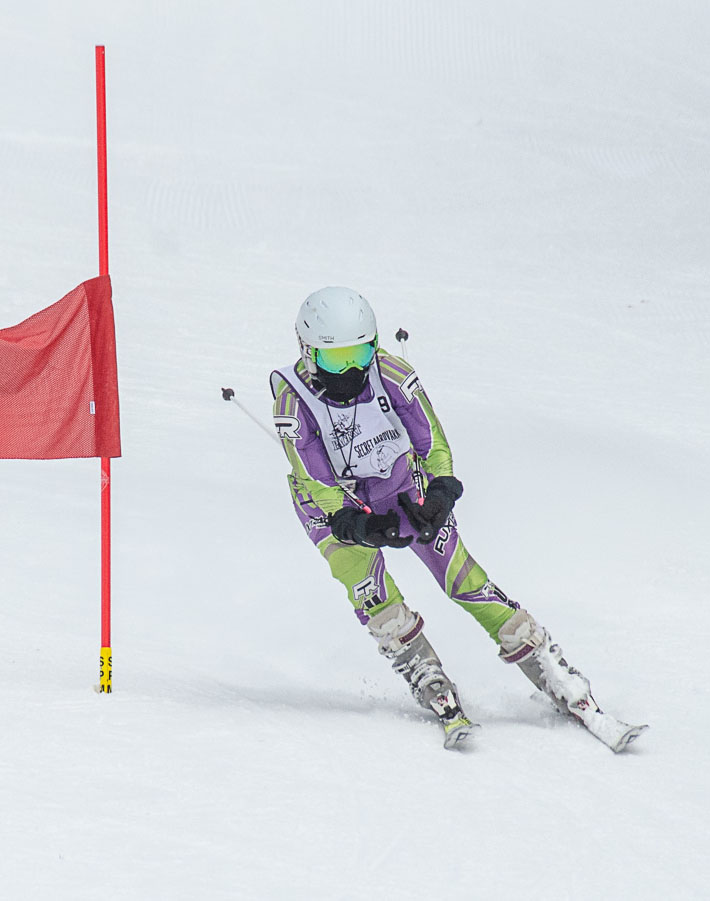 Person skiing down a ski race course wearing a Secret Aardvark jersey