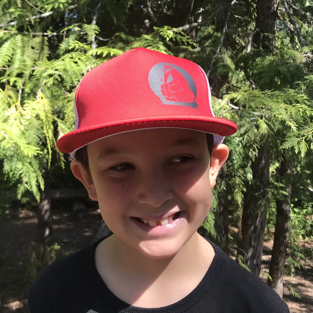 Child wearing red Secret Aardvark trucker hat with Black Secret Aardvark logo