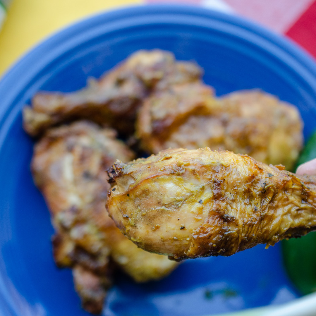 A pile of grilled chicken legs with bright yellow Serrbanero Mustard BBQ Sauce.