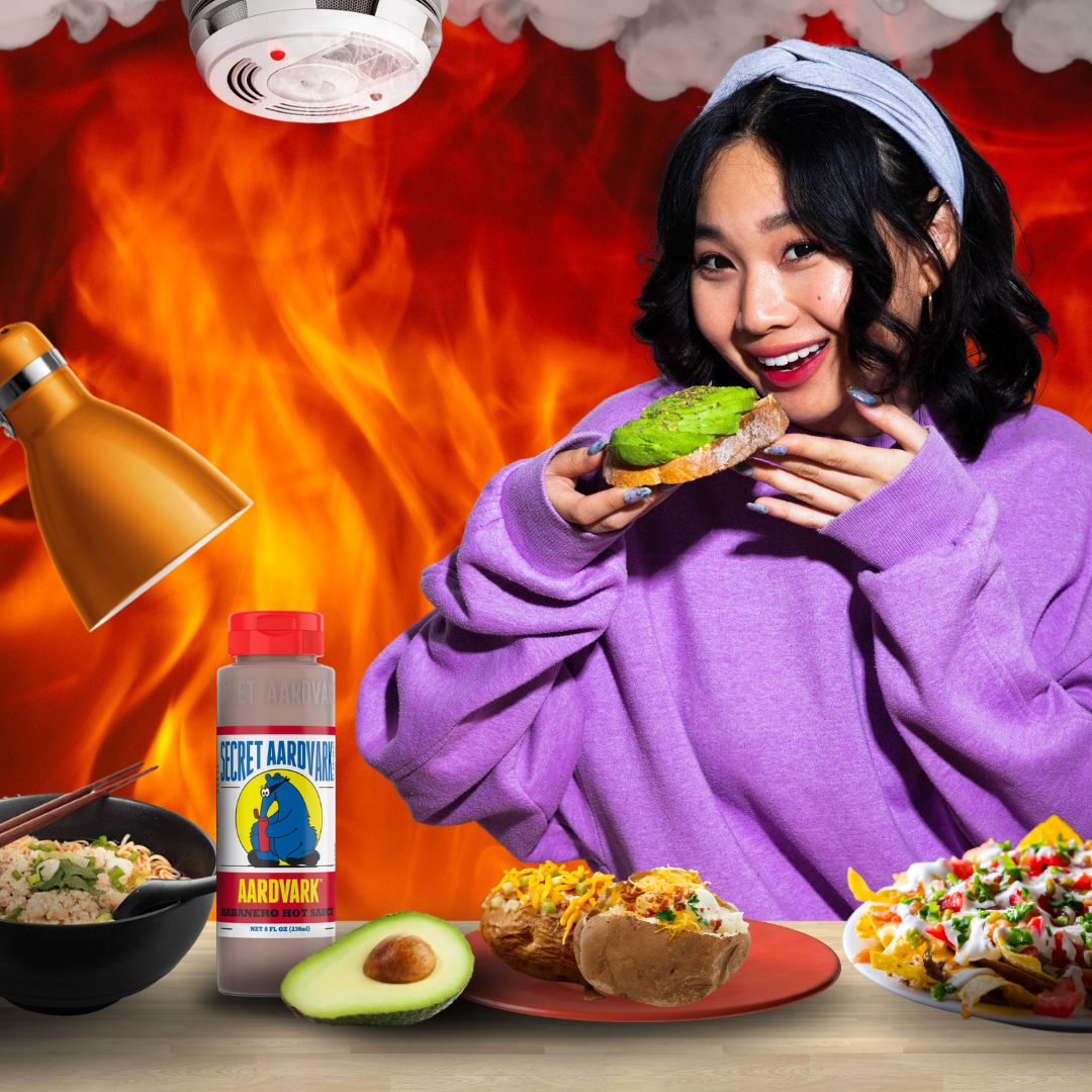A female college student surrounded by food, Aardvark hot sauce, with flames and a smoke detector in the background.