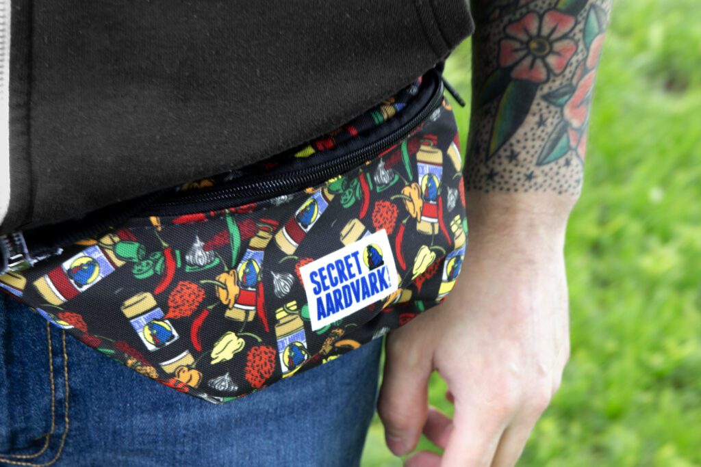 Close up of fanny pack on wait. The pack has secret aardvark's log with peppers and bottles of sauce.