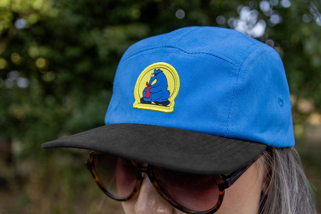 Blue Aardvark Camper hat on female head. Hat is blue with an Aardvark patch in the center