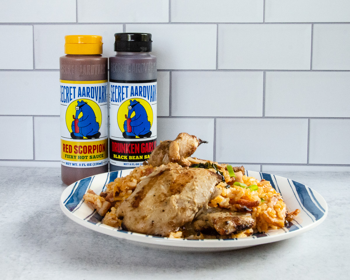 A plate piled with Asian-style grilled chicken and a side of kimchi friend rice.