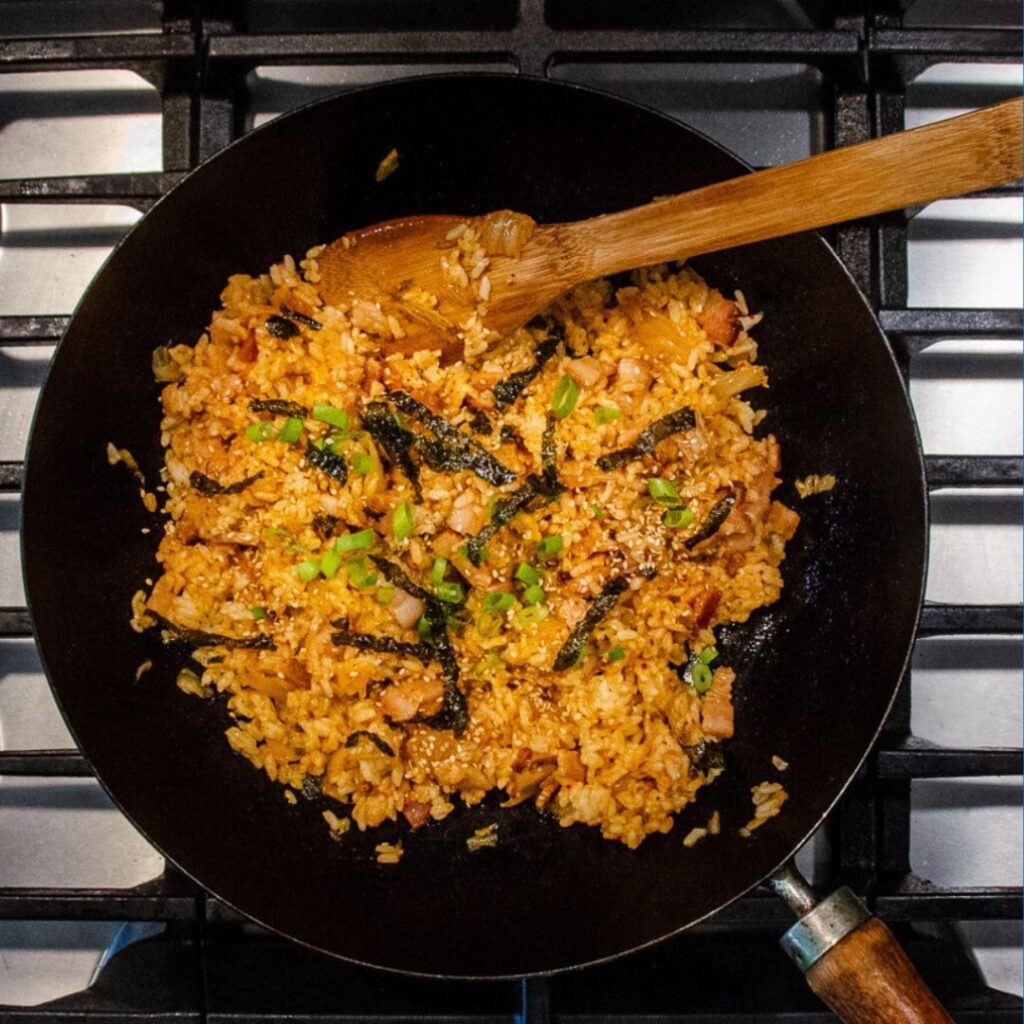 A skillet full of delicious kimchi fried rice featuring our Red Scorpion Fiery Hot Sauce.