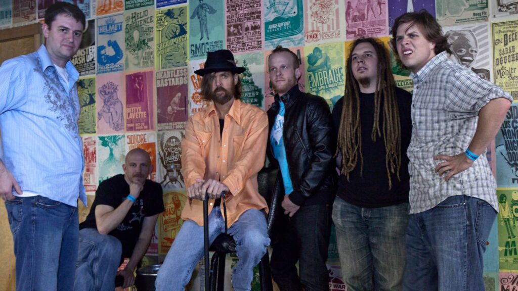 Scotland Barr and the Slow Drags posed against a wall of band posters.